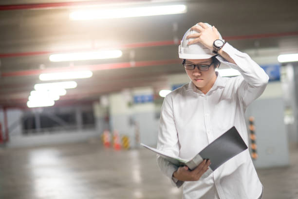 istock Young Asian Engineer or Architect holding files while wearing personal protective equipment safety helmet at construction site 860854446