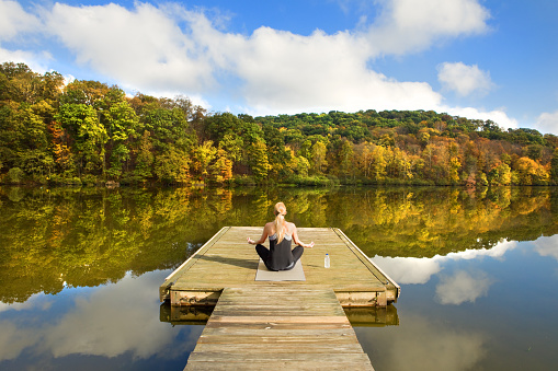 A woman enjoying a beautiful fall day on a boat dock for meditation.