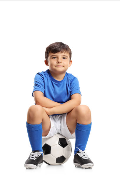 istock Boy in a blue jersey sitting on a football 860866512
