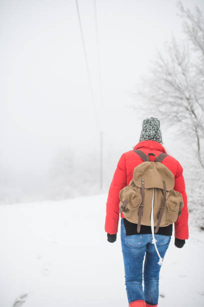 istock Woman with a backpack walking through winter forest. 860874094