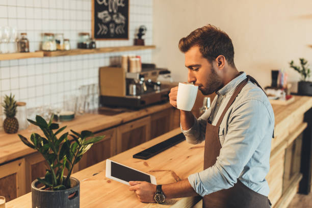 istock barista with cup of coffee using tablet 860874356