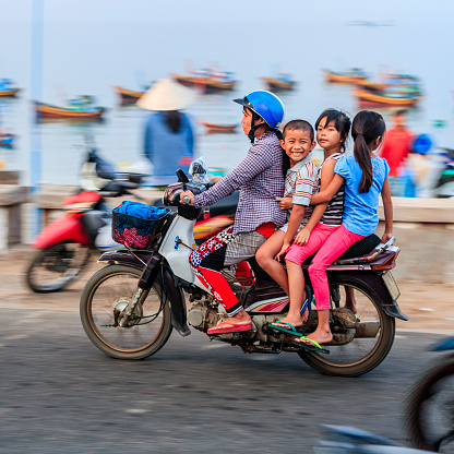 Madre vietnamita con niños montando una motocicleta, Vietnam del sur photo