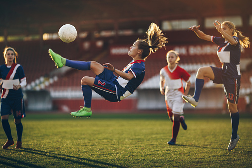 Dedicated female soccer player doing the bicycle kick on a soccer match at a stadium.