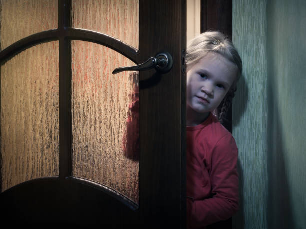 istock A child Peeps standing behind a door in a dark room 860884296