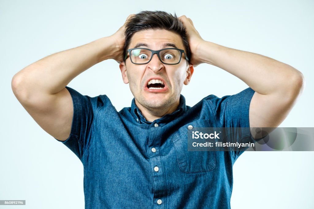 Man with shocked, amazed expression isolated on gray background Bizarre Stock Photo