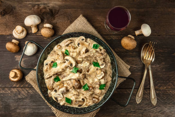 Mushroom beef stroganoff with red wine on rustic textures Mushroom beef stroganoff with cremini and champignons, with a glass of red wine, a fork, and a spoon, shot from above on dark rustic textures with a place for text crimini mushroom stock pictures, royalty-free photos & images