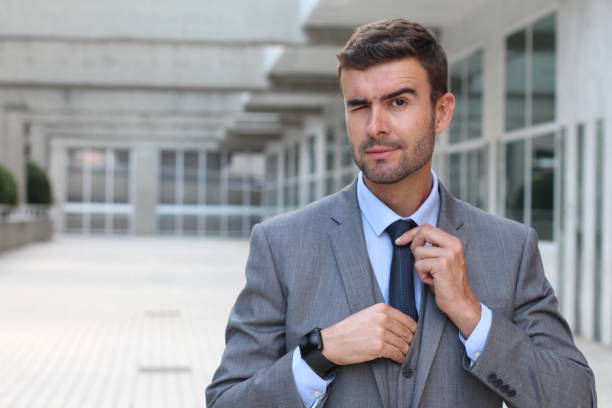 istock Elegant businessman winking while adjusting his tie 860900308