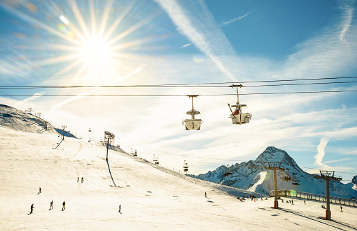 Ski resort glacier and chair lift in french alps - Winter vacation and sport travel concept - Snowboard season opening and people having fun on mountain - Warm afternoon color tone