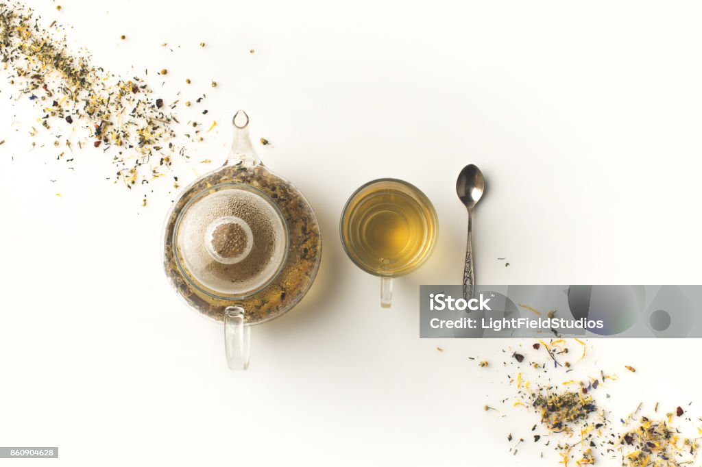 herbal tea in cup and kettle top view of fresh organic herbal tea in glass teapot and cup on white Tea - Hot Drink Stock Photo