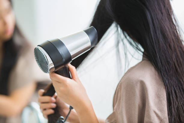 髪を熱にヘアー ドライヤーを持つ女性。 - 衣類乾燥機 ストックフォトと画像