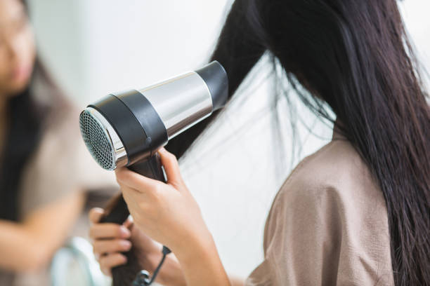 Woman with a hair dryer to heat the hair. stock photo