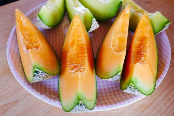 Close up fresh sliced melon with plate on wooden background at melon farm in Furano, Hokkaido, Japan. Close up fresh sliced melon with plate on wooden background at melon farm in Furano, Hokkaido, Japan. Juicy summer sweet fruit. yellow melons field stock pictures, royalty-free photos & images