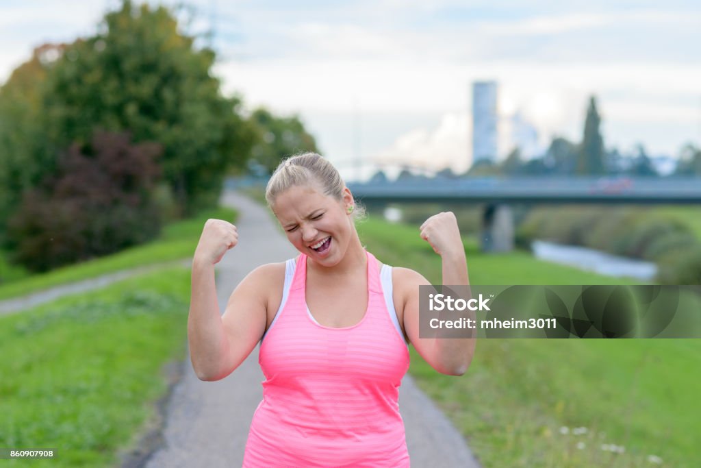 Jeune femme heureuse, levant les mains pendant la course - Photo de Surpoids libre de droits