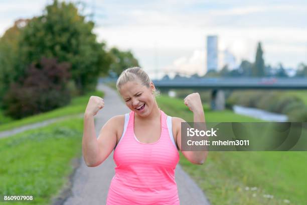 Photo libre de droit de Jeune Femme Heureuse Levant Les Mains Pendant La Course banque d'images et plus d'images libres de droit de Surpoids