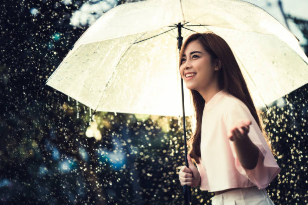 アジアの女性が、雨を待っている彼女は傘を持っていた。 - umbrella women storm yellow ストックフォトと画像