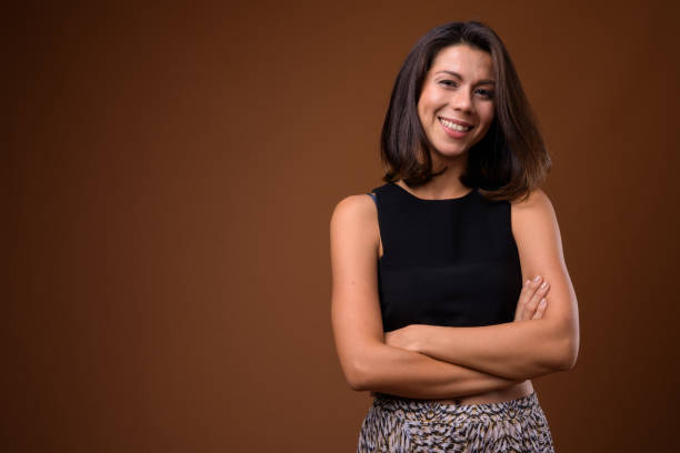 Studio shot of beautiful multi-ethnic businesswoman with short hair against colored background Studio shot of beautiful multi-ethnic businesswoman with short hair against colored background horizontal shot sleeveless top stock pictures, royalty-free photos & images