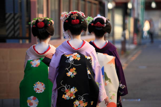 Back view of three geishas Hanamikoji, Kyoto City, Japan - Oct 6, 2010: The backview of three geishas, who were going for their appointment at dusk in Kyoto, Japan. geisha costume stock pictures, royalty-free photos & images