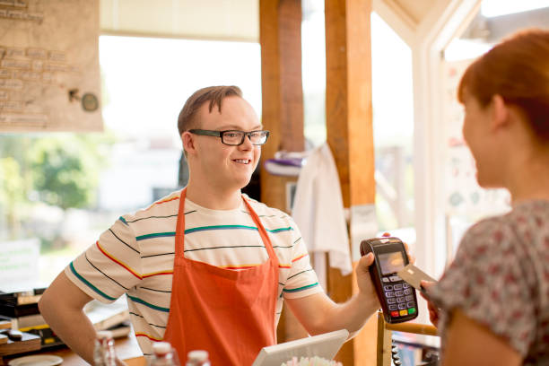 Making a Payment in the Farm Cafe A woman makes a purchase in a farm cafe via contactless payment. down syndrome photos stock pictures, royalty-free photos & images