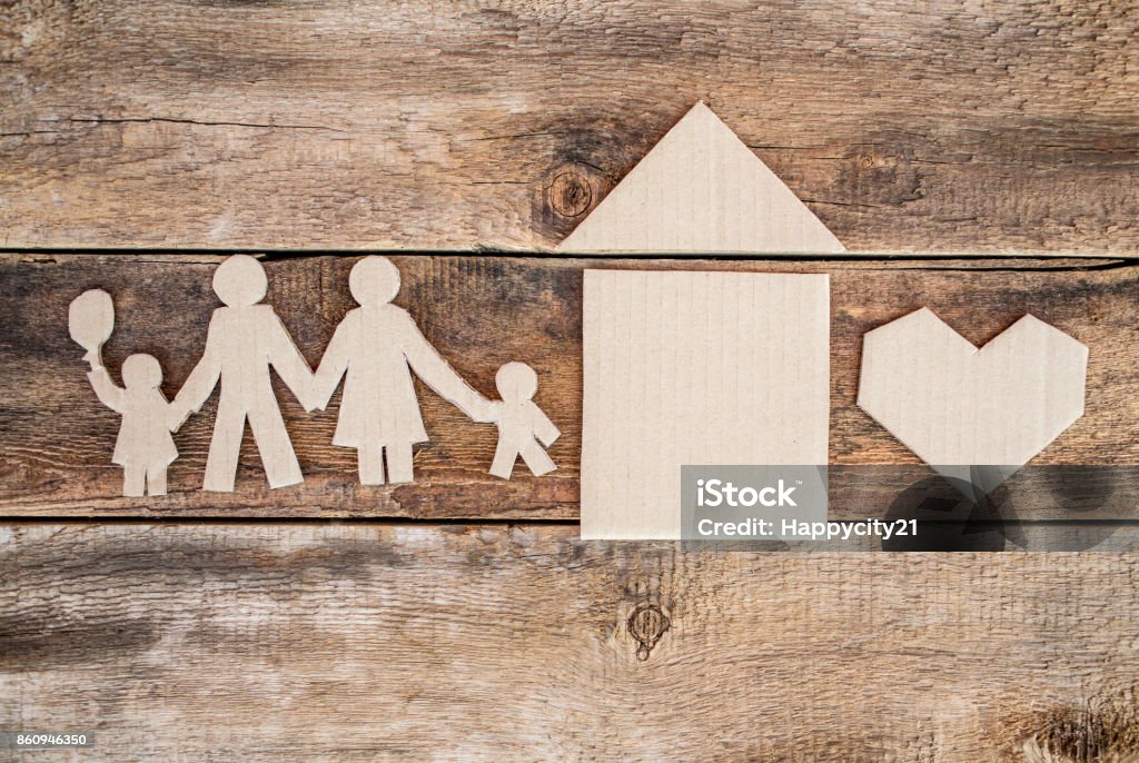 Happy paper family Happy paper family with house and heart cut out over wooden background Adoption Stock Photo