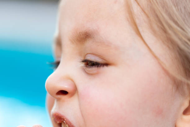 istock Young girl outside eating a cookie looking down 860947368