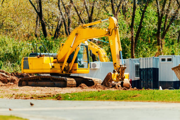 istock Backhoe works on leveling of ground next to container offices 860957222