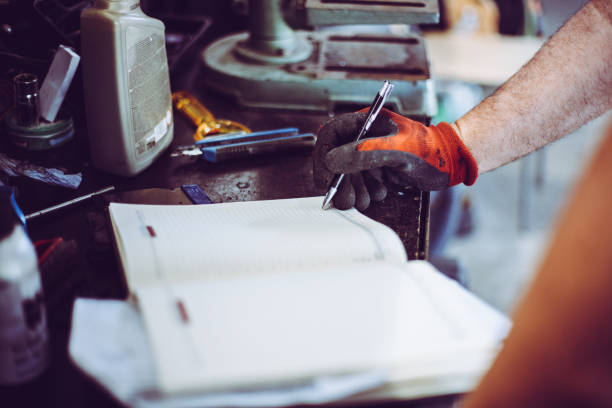 istock Senior man in workshop. Man writing obligations in his notes. Close up. 860957488