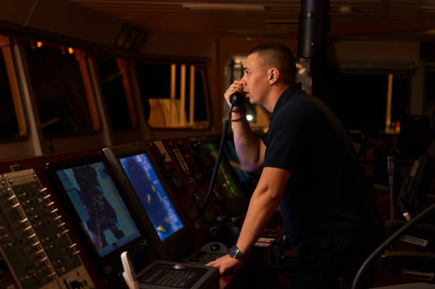 Navigator / Pilot on the bridge of the vessel Navigation officer / Pilot on bridge of a vessel underway on the watch with radio, binocular and coffee marines navy sea captain stock pictures, royalty-free photos & images