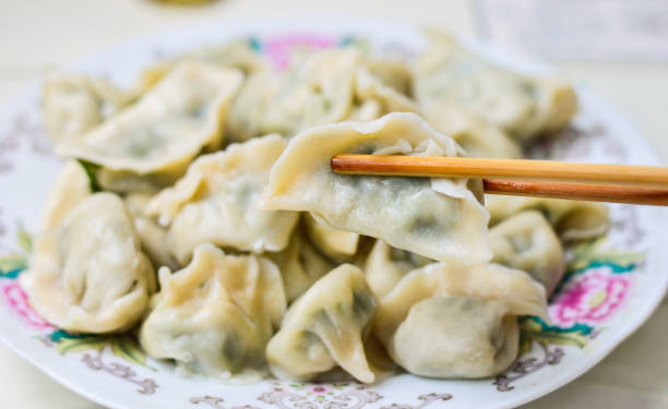 Chopsticks Pick Up Boilded Chineses Dumplings from a Plate stock photo