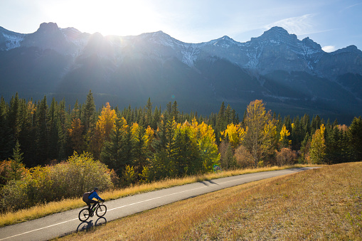 A male bike commuter rides the Trans Canada Trail bike path near Canmore, Alberta, Canada in the fall.
