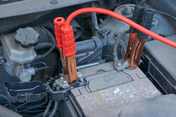 istock charging automobile battery with another car jumper cables at winter 860959122
