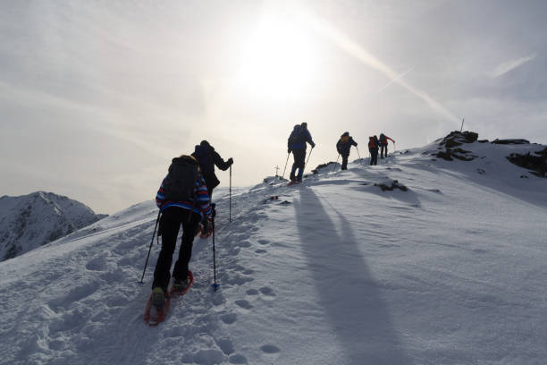 group of people hiking on snowshoes and mountain snow panorama with summit cross in stubai alps, austria - summit cross imagens e fotografias de stock