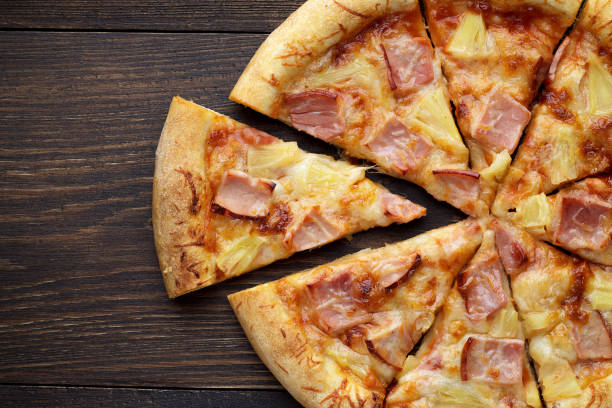 istock Sliced hawaiian pizza with ham and pineapple on dark wooden table. 860986172