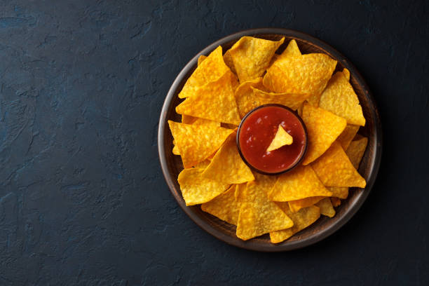 Nachos with dip sauce in a plate on dark stone blue background. stock photo