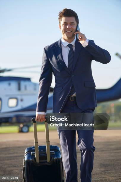 Businessman Walking Away From Helicopter Whilst Talking On Mobile Phone Stock Photo - Download Image Now