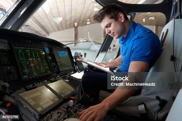 Male Aero Engineer With Clipboard Working In Helicopter Cockpit Stock Photo - Download Image Now