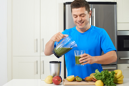 Male Athlete Making Juice Or Smoothie In Kitchen