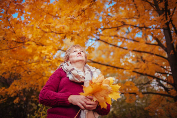 istock Middle-aged woman gathers maple leaves 861022890