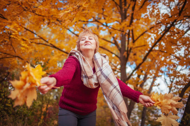 istock Middle-aged woman gathers maple leaves 861022916