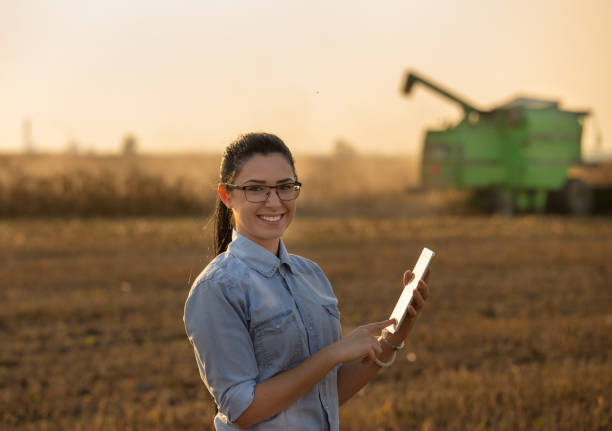 Agronomist with tablet in front of combine harvester