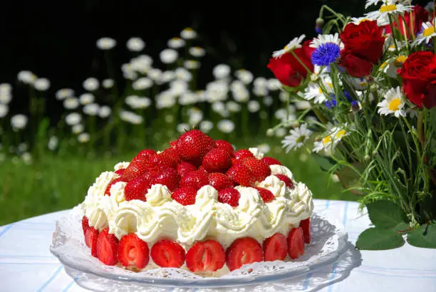Summer objects in a garden -  strawberry cake and a bouquet with summer flowers