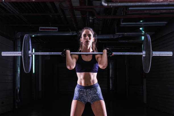 Woman Lifting Weights in Gym Attractive young fit sportswoman working out in training gym lifting Barbell stock pictures, royalty-free photos & images