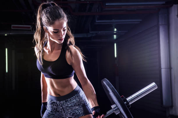 Attractive young fit sportswoman working out with weights Attractive young fit sportswoman working out with weights body building photos stock pictures, royalty-free photos & images