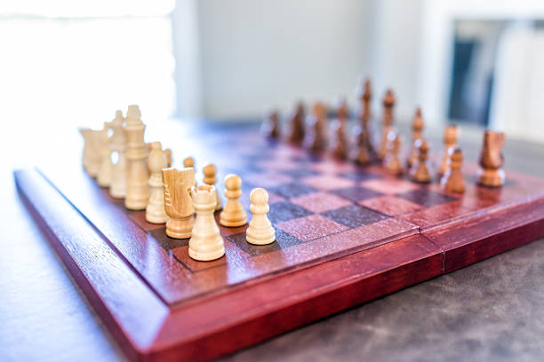 closeup, d’échiquier avec des morceaux de bois sur la table en plein soleil - chess board room business strategy photos et images de collection