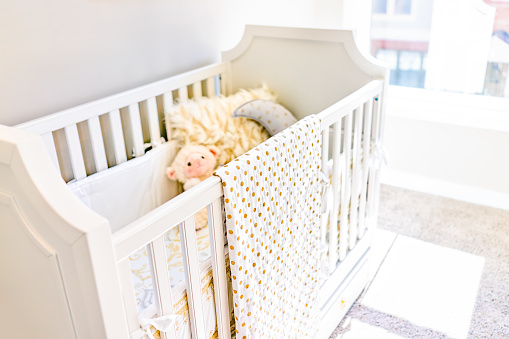 Closeup brillante amarillo bebé cuna en Habitación infantil con juguetes y la almohadilla de montaje modelo casa, apartamento o casa photo