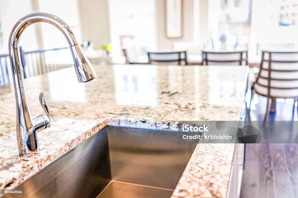 New modern faucet and kitchen room sink closeup with island and granite countertops in model house, home, apartment Granite - Rock Stock Photo