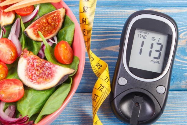 Fruit and vegetable salad and glucose meter with tape measure, concept of diabetes, slimming and healthy nutrition Fruit and vegetable salad, glucometer with result of measurement sugar level and tape measure, concept of diabetes, diet, slimming, healthy lifestyles and nutrition centimeter photos stock pictures, royalty-free photos & images