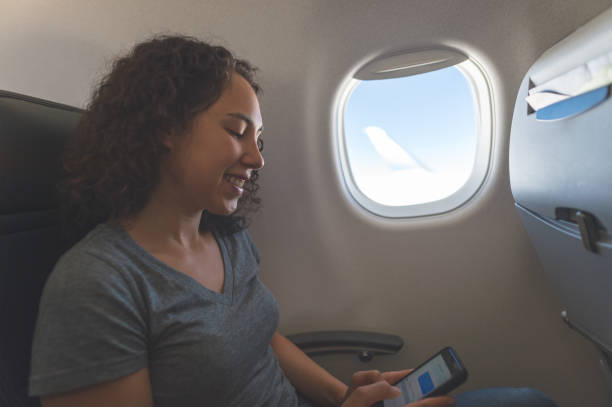 istock Young Eurasian woman cell phone while seated by a window on an airplane 861064594