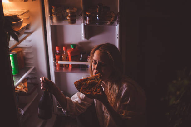 junge frau trinken und essen spät in die nacht - bulimia stock-fotos und bilder