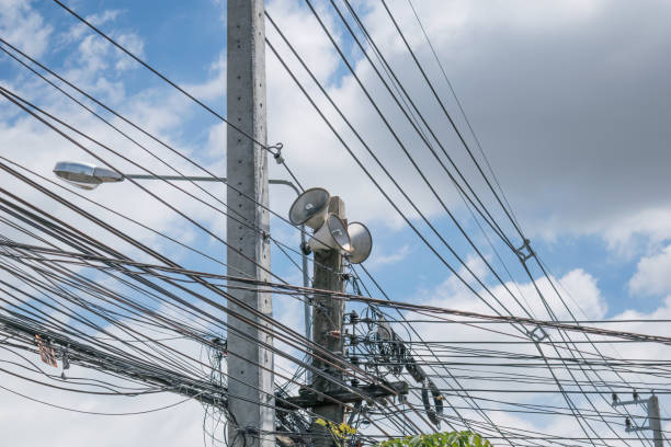istock Many wires messy with power line cables and electric pole on cloud blue sky background 861084102