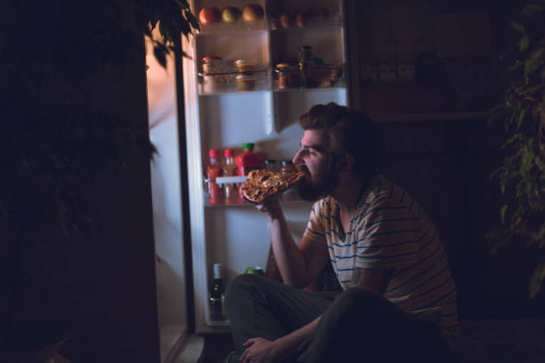 Handsome man eating pizza late night Handsome man eating pizza late night bulimia stock pictures, royalty-free photos & images